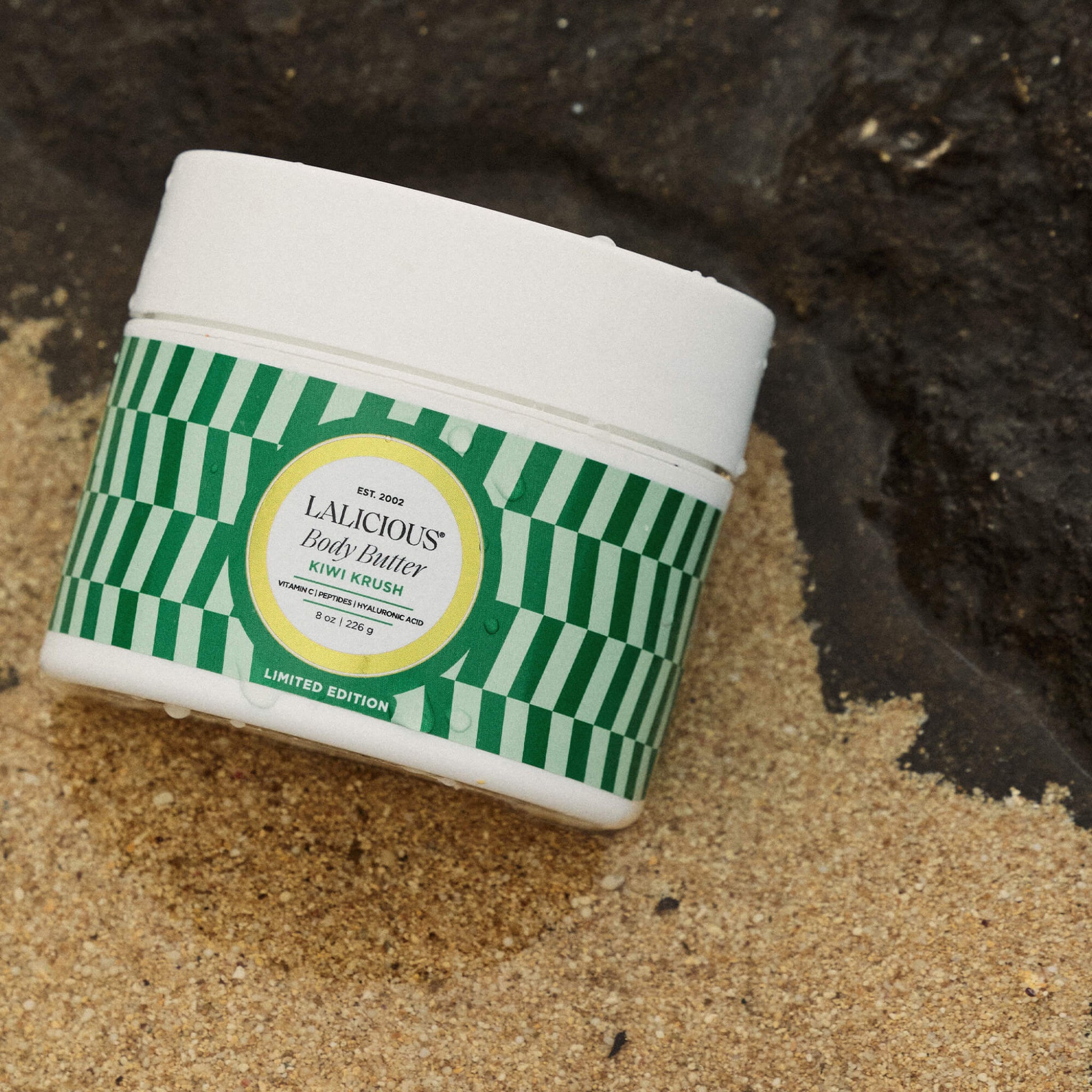 Kiwi Krush 8oz Body Butter jar on a sandy beach - LALICIOUS