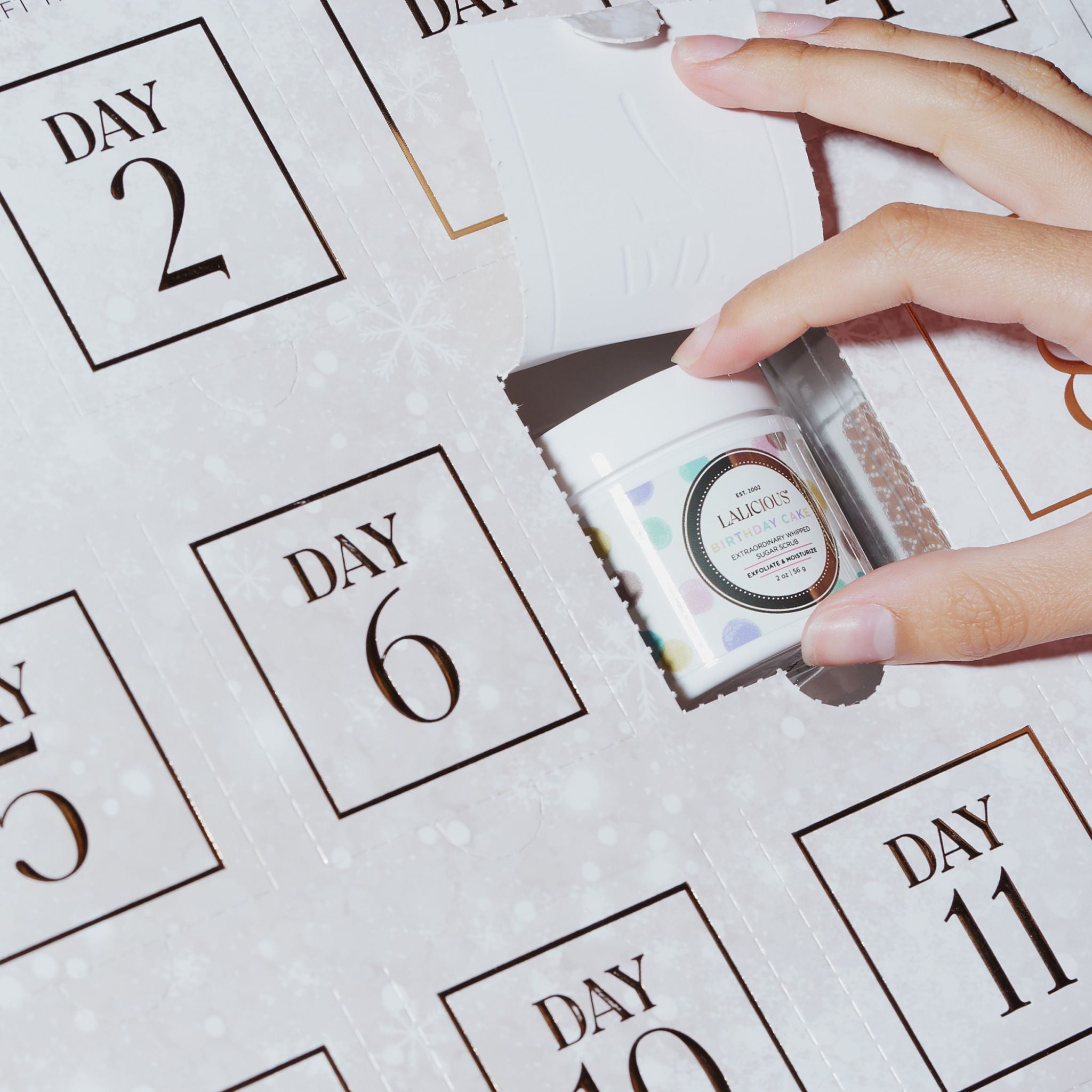 Advent Calendar - LALICIOUS with a hand taking out a product on an opening.