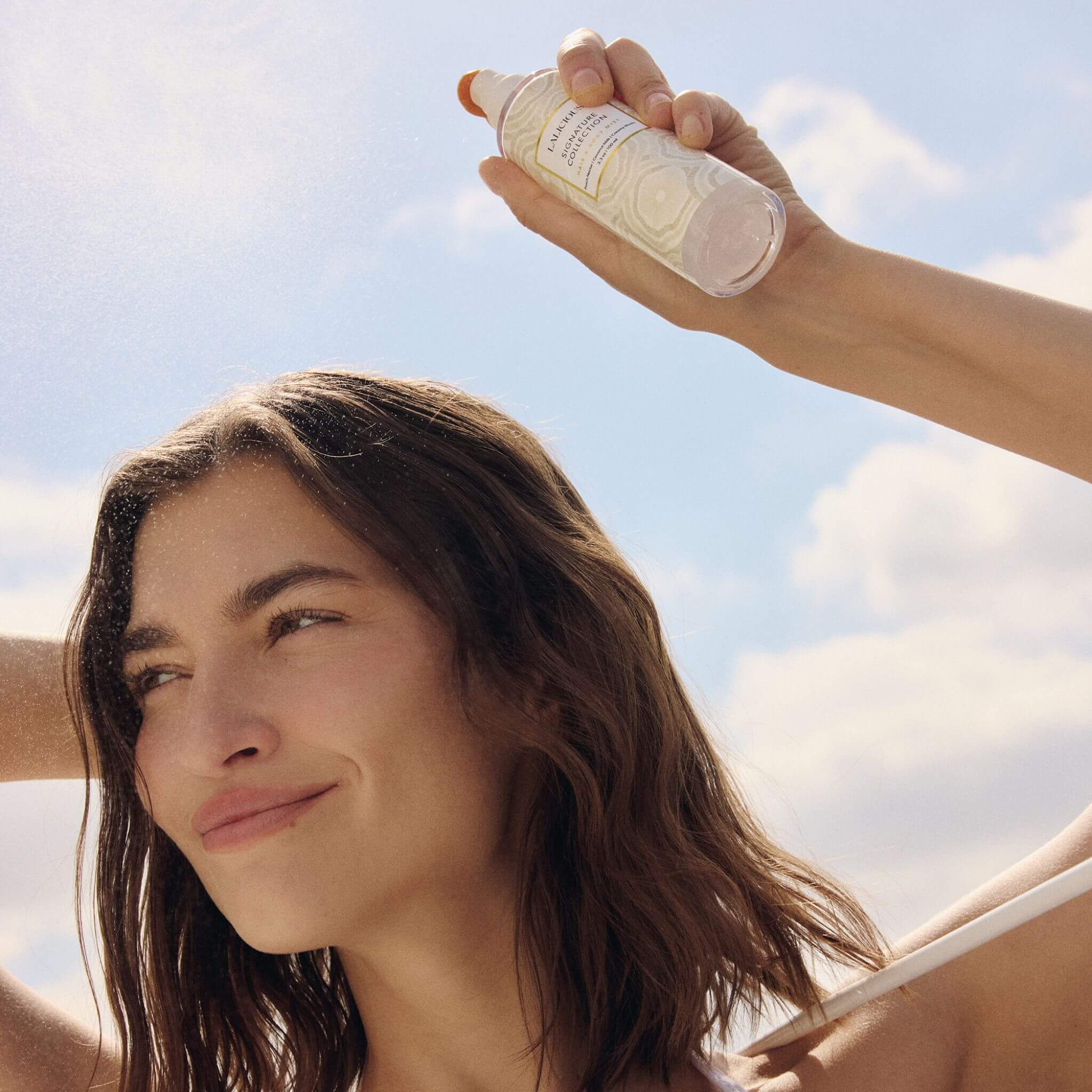 Woman spraying Signature Collection Hair & Body Mist  on hair outdoors- LALICIOUS