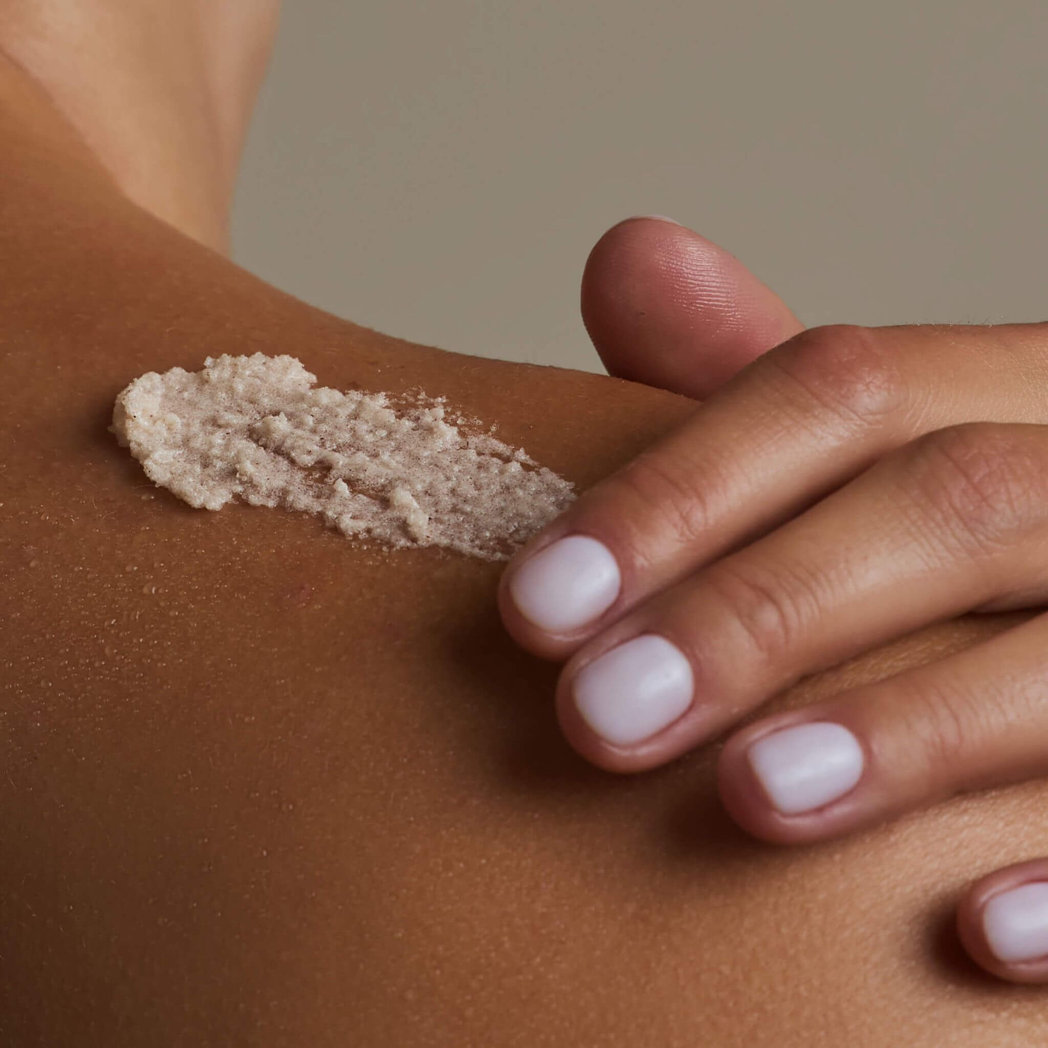 Close-up hand applying Sugar & Spice Scrub on shoulder LALICIOUS